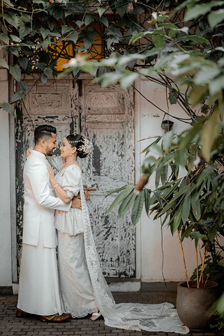 Couple embracing in front of a weathered door framed by leaves